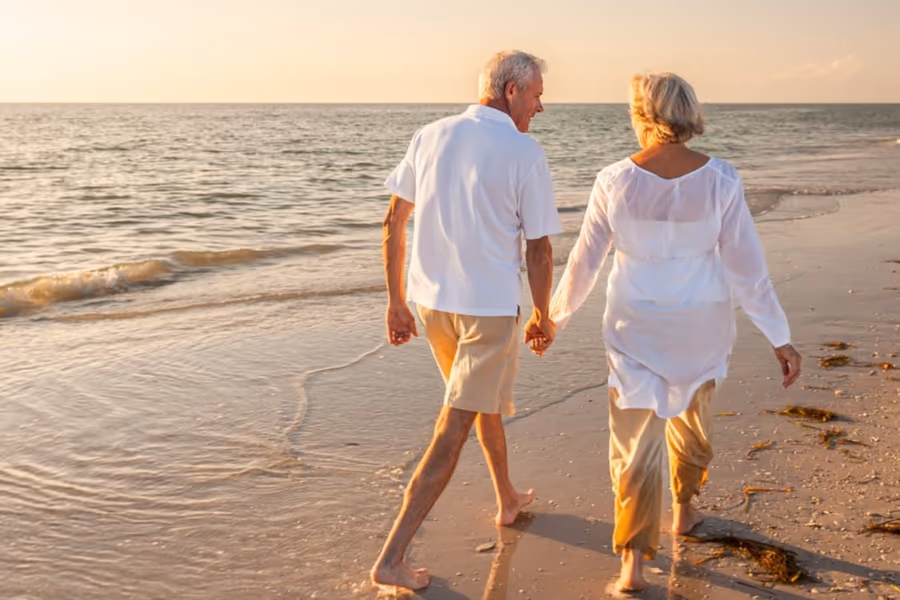 Casal idoso caminhando na praia — vida ativa recuperada após a cirurgia de catarata. Casal idoso caminhando na praia — vida ativa recuperada após a cirurgia de catarata.