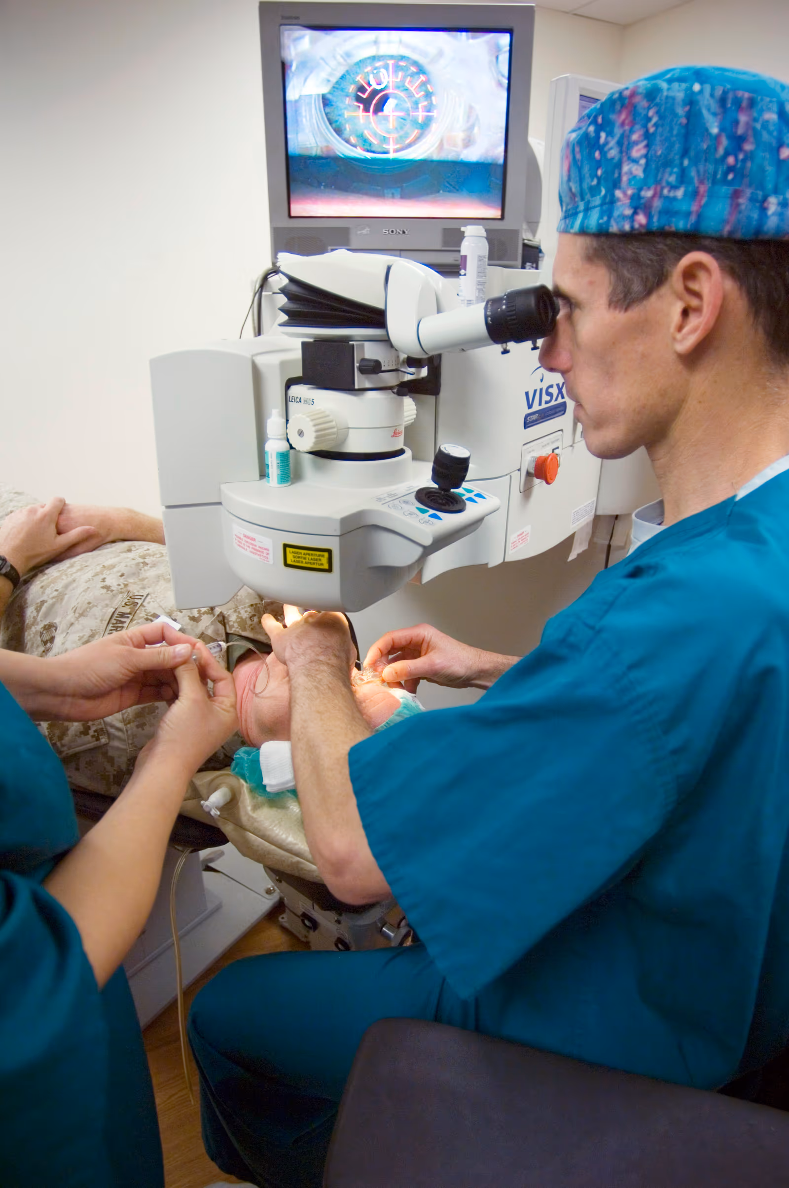 Oftalmologista posicionando o laser de excimer sobre o olho de um paciente antes da cirurgia LASIK (IntraLase). Fonte: U.S. Navy / Mass Communication Specialist 1st Class Brien Aho, via Wikimedia Commons. Domínio público.